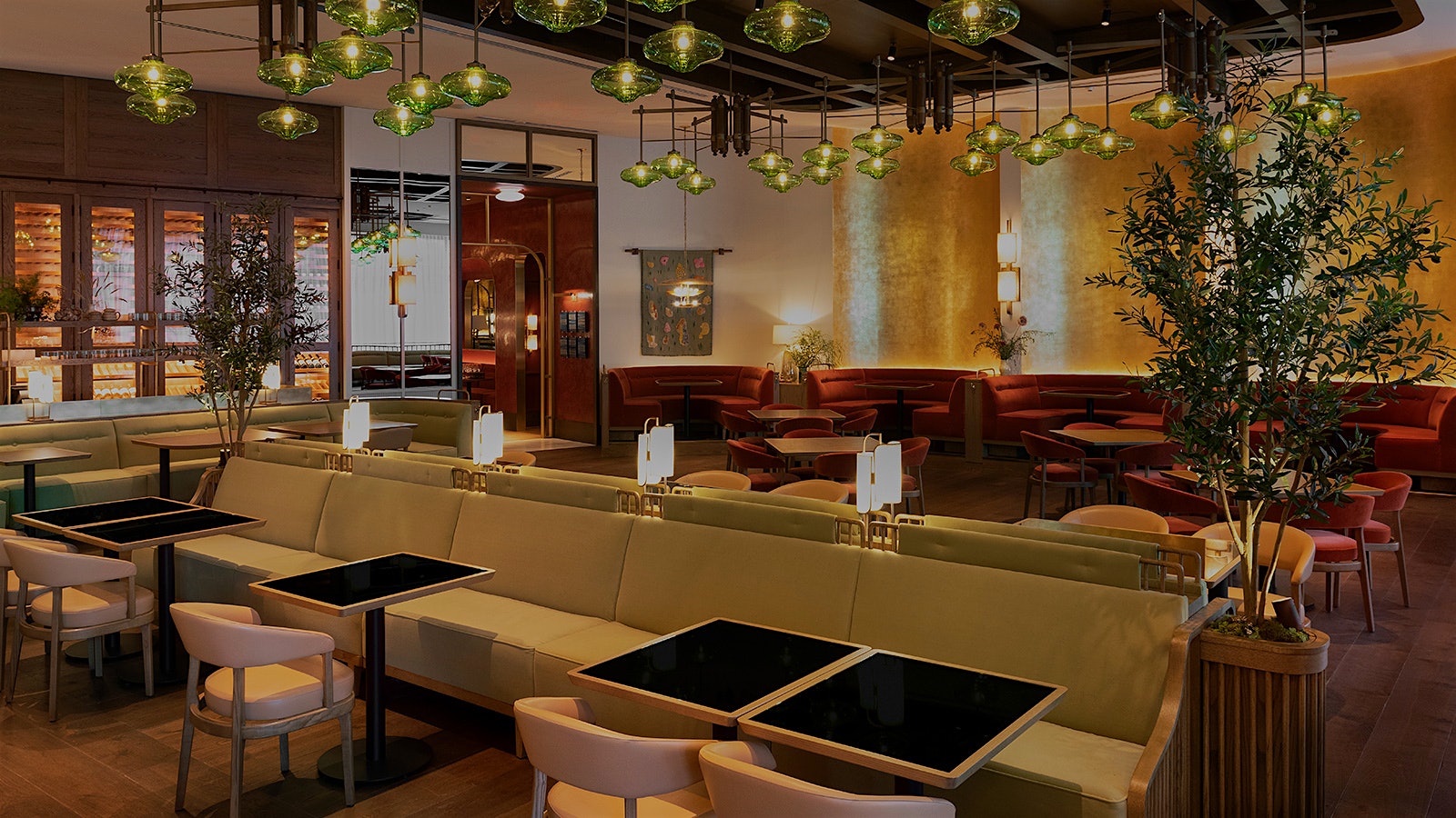  El comedor del restaurante Mara, de inspiración mediterránea, con luces de cristal verde y bancos y sillas en tonos rojos y dorados